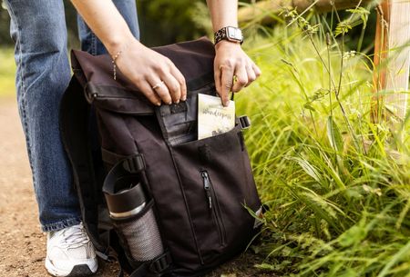 Frau steckt ihren Wanderpass in den Rucksack