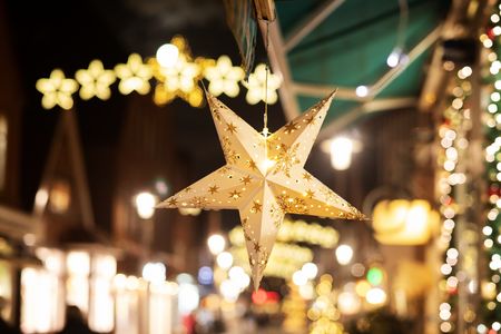 Weihnachtsanhänger Stern hängt vor Lichtern auf dem Weihnachtsmarkt