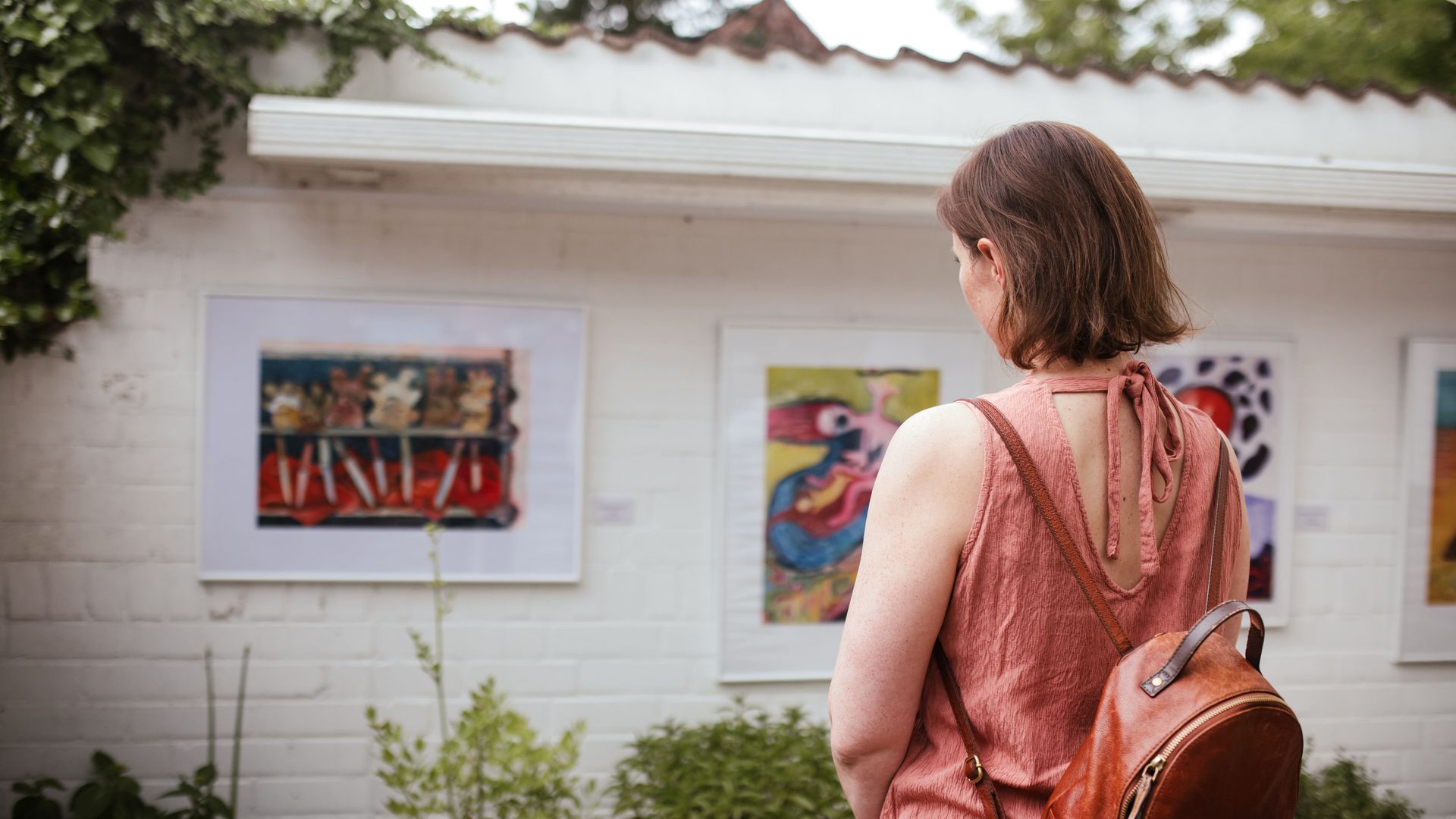 Frau schaut Bilder an der Wand im Garten an