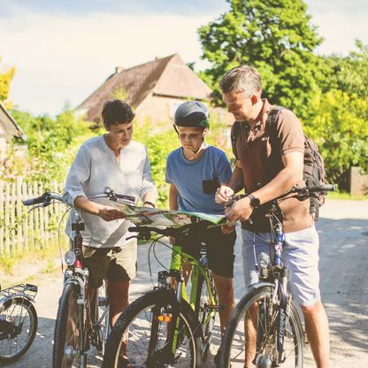 Familie mit Fahrrädern schaut auf Landkarte