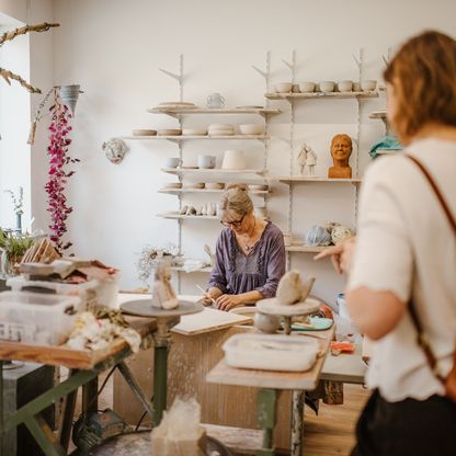 Besucherinnen schauen Töpferei Künstlerin zu bei der Arbeit