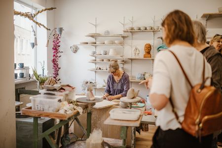 Frau töpfert und Besucherinnen schauen zu