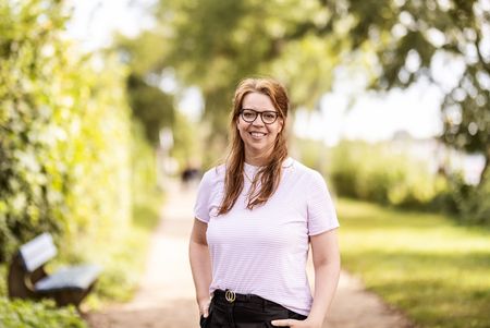 Frau mit weißem T-Shirt vor grünen Bäumen