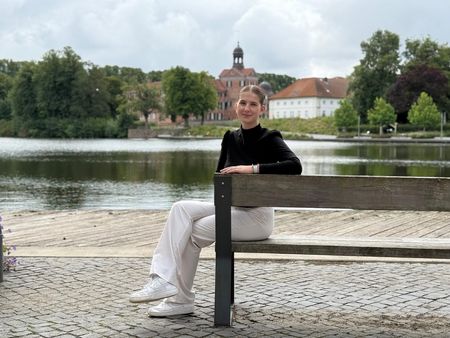 Lilli Reimansteiner, die eine Ausbildung zur Veranstaltungskauffrau macht, sitzt auf einer Bank am Großen Eutiner See.