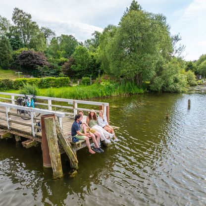 Radfahrer machen Pause auf einem Steg am See